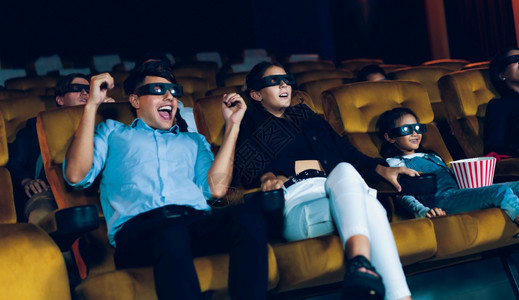 一群人在电影院看三维眼镜的电影有兴趣观看屏幕奋和吃爆米花图片