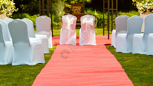 许多婚席在绿草和长的红地毯上盖着白色优雅的封面配偶在中间背景图片