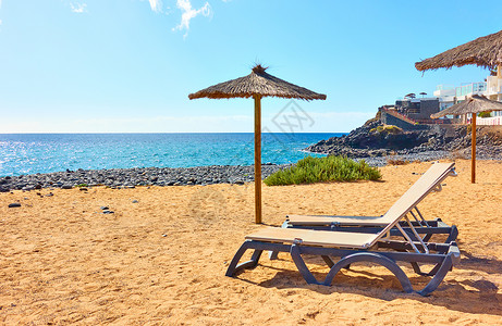 在阳光明媚的夏日桑迪海滩上有阳伞和光沙滩海边有阳伞和日晒背景图片