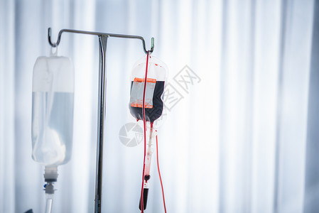 血袋和输血管关闭红血袋和在医院病房中吊挂的正常盐碱背景