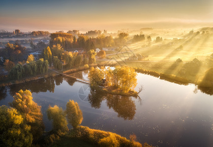 吃亏是福湖边小岛上有丰富多彩的树木房屋空中景象秋天是福吉的日出美丽景色与雾中村庄金色的太阳光束水中的反射在乌克兰倒塌背景