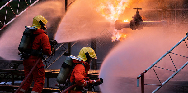 全景消防队使用水雾喷射灭火器来对付石油管道泄漏和钻机天然气站爆炸造成的火焰气体高清图片素材