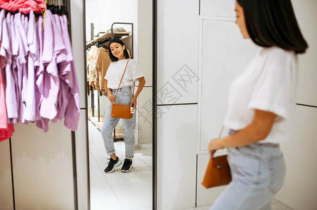 在服装店买手袋的女子在时装店商购物的女子在镜里偷窥的女在服装店买手袋的女子生活方式高清图片素材