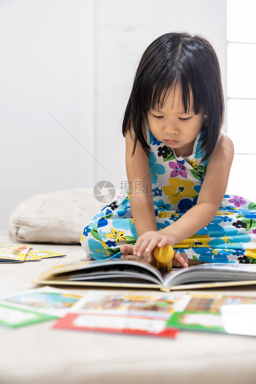 亚洲女童在家里客厅阅读互动式书作为家庭学校教育而城市则因为全世界流行的可口19流行病而被封锁图片