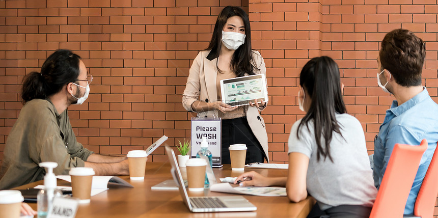 亚洲商业女在集思广益的会上介绍她工作们戴着保护面罩在新的正常办公室里防止冠状新冠19的传播网络横幅适合图片