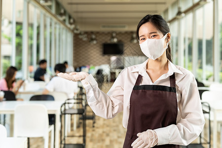 具有吸引力的肖像亚洲女服务员戴面孔顾客背景坐在室内餐厅的社会距离桌子上背景图片