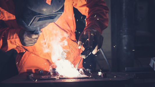 金属焊工与电弧接机一起工作在厂焊接钢材同时佩戴安全设备图片