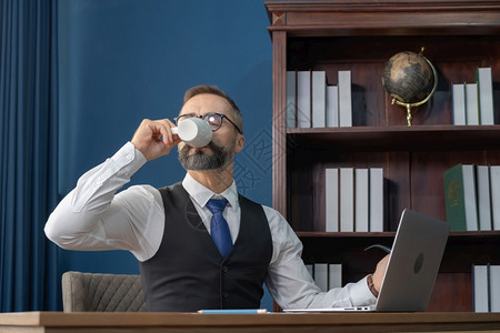 金发白人种在办公室工作喝咖啡及电脑笔记本电脑图片