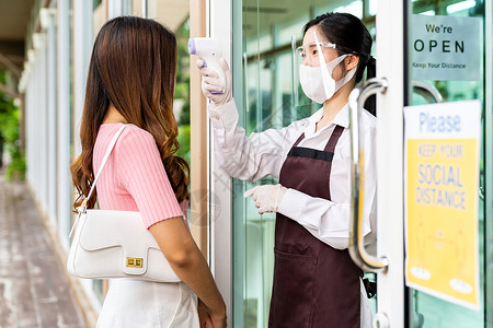 亚洲女服务员在进餐前面给女顾客测量温度高清图片