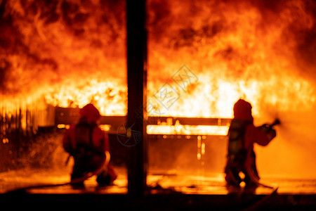 消防员使用水雾灭火器在大型建筑中使用灭火器与焰战斗消防员和工业安全灾害及公共服务概念摘要背景模糊背景图片