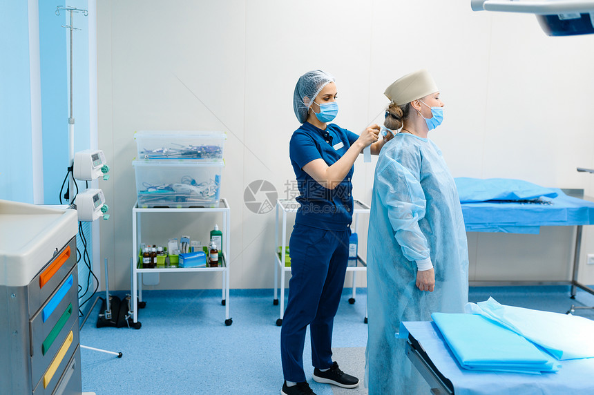 手术室女外科医生和手术室女助理为手术做准备穿制服的医生门诊人员医药和保健院的手术室女外科医生和助理图片