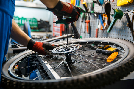 自行车轮胎工场的自行车组装人安制动磁盘机械师在制服上修车周期有问题专业自行车修理服务工场的自行车组装人安刹车背景