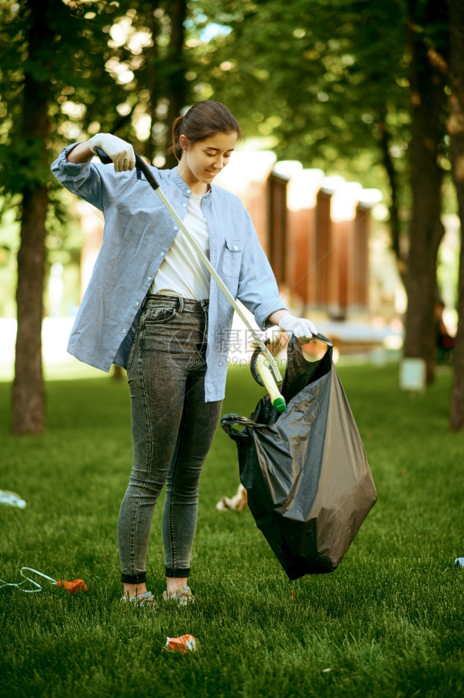 年轻女在公园的塑料袋中收集垃圾从事志愿工作男清洁森林生态恢复活方式垃圾收集和回生态护理环境清洁图片