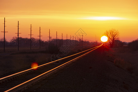 钢铁轨反射太阳的金光朝向日落时的地平线背景图片