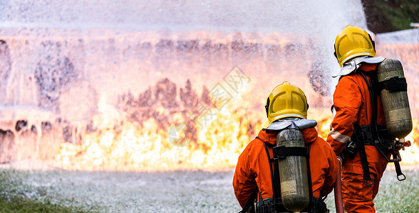 使用化学泡沫灭火器来对付油轮卡车事故的火焰全景消防员安全事故和公共服务概念背景图片
