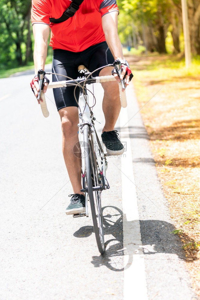 Asian男骑自行车运动员在农村路上骑着运动器械衬衫骑车背景是绿树周末户外运动员和健身概念图片