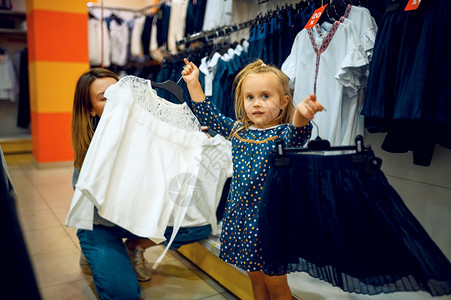 母亲和女孩在商店中挑选衣服图片