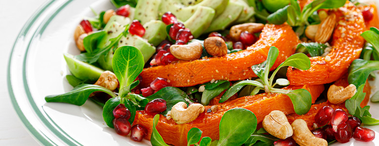 新鲜蔬菜沙拉配有羊羔生菜烤花瓜或南鳄梨石榴腰果和杏仁健康素食品概念图片