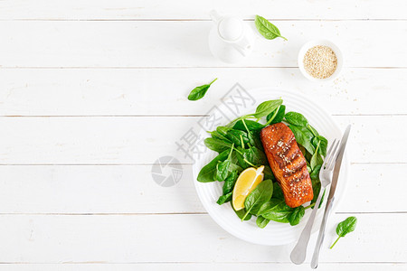 沙门鱼肉片烤和新鲜菠菜沙拉在午餐盘上图片
