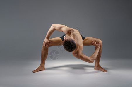 我很强壮男瑜伽的姿势很困难完美的伸展冥想灰色背景强壮的人在做瑜伽练习麻训高度集中健康的生活方式瑜伽的姿势很困难完美的伸展背景