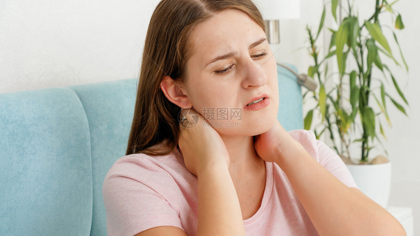 睡衣女青年在不舒服的床上或枕头后颈部和背疼痛图片