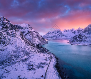 美丽的雪山海路天空的中景象冬季日落时有粉色云雾挪威洛福滕岛最上面的公路雪中岩石海岸冷水从上面看自然背景