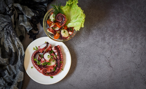 乌鱿鱼和章触手沙拉蔬菜柠檬番茄辣菜和盘子碗的香料图片