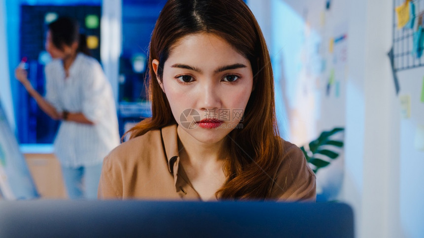 亚洲女商人在预防的新正常情况下在办公室晚上工作时使用笔记本电脑在网上工作加班时在新的正常情况下在社会上感到快乐科罗纳后的生活和工图片
