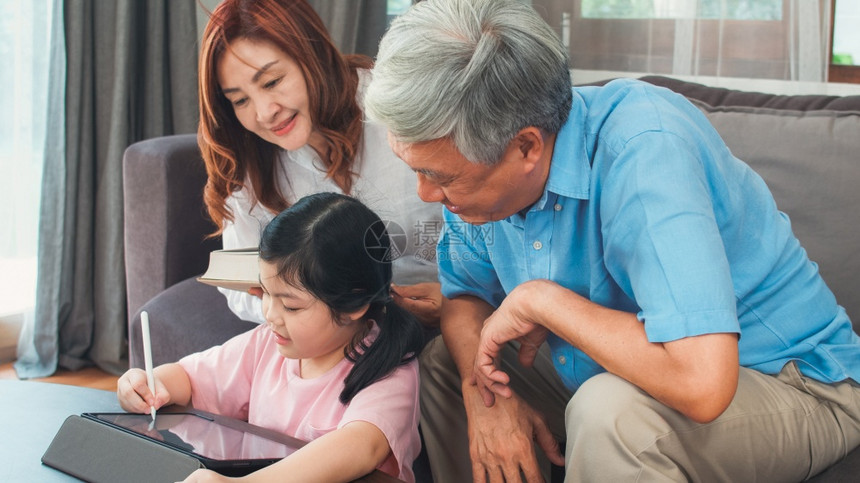 亚洲祖父母和外孙女在家的视频电话高级人外公和祖母对女孩使用手机视频电话与在家客厅的爸和妈交谈感到快乐图片