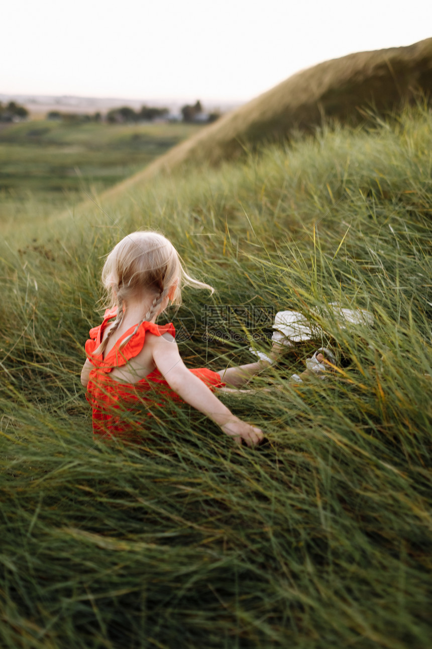 穿着红衣的儿童在日落时绿草地上玩耍家庭节假日和时间在一起的概念暑假时一个美丽的女孩肖像图片
