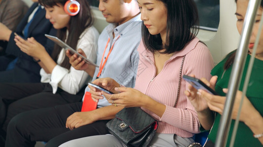 在公共地下列车中使用移动电话的年轻人城市生活方式和亚洲通勤概念图片