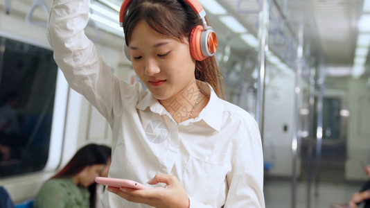 在公共火车上使用移动电话的年轻妇女移动电话图片