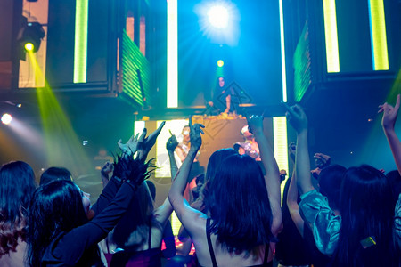 一群人在迪斯科夜俱乐部跳舞音从DJ在舞台上播放新年晚宴和夜生活概念一群人在迪斯科夜俱乐部跳舞音从DJ在舞台上播放背景图片