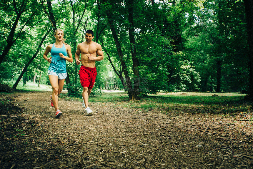 快乐的年轻夫妇在森林中奔跑图片
