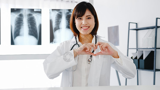 充满自信的年轻亚洲女医生身穿白色疗制服带着手指做心脏势微笑着工人高清图片素材