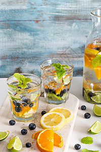 柠檬水或mojitos柠檬橙蓝莓和薄荷食用脱毒饮料光底眼镜的柑橘柠檬橙蓝莓和薄荷食用脱毒饮料的夏季健康鸡尾酒背景
