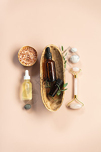 天然SPA化妆品背景装有几瓶基本油海盐和粉色底的按摩滚机平板背景图片