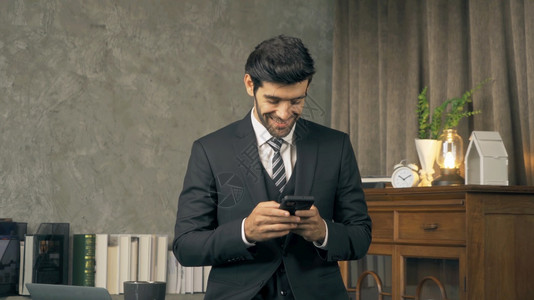 中东部人CEO在家工作使用移动智能手机在技术设备通信概念中传递短信图片