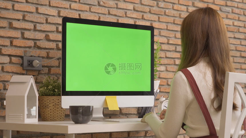 亚洲女商人在家工作的年轻人在网络摄像头视频电话会议上用计算机和空白绿屏间在桌上工作冠状概念的隔离中工作图片