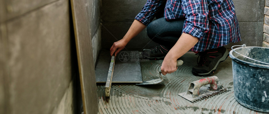 女砖匠用一层的地板检查安装瓷砖图片