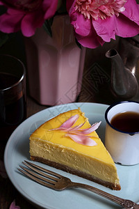 芝士蛋糕在盘子和杯上樱桃一束花附近图片