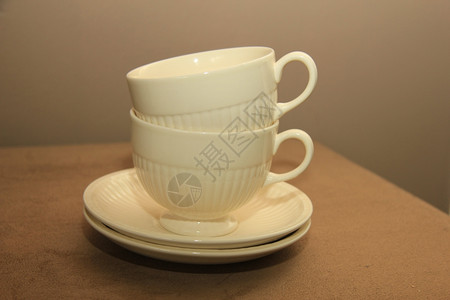两个经典的白茶杯堆在一个蜜蜂花瓶上背景图片