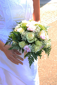 新娘抱着她的花束象牙玫瑰和粉红纤维背景图片