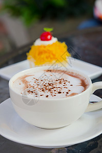 加热卡布奇诺白咖啡杯和甜蛋糕图片