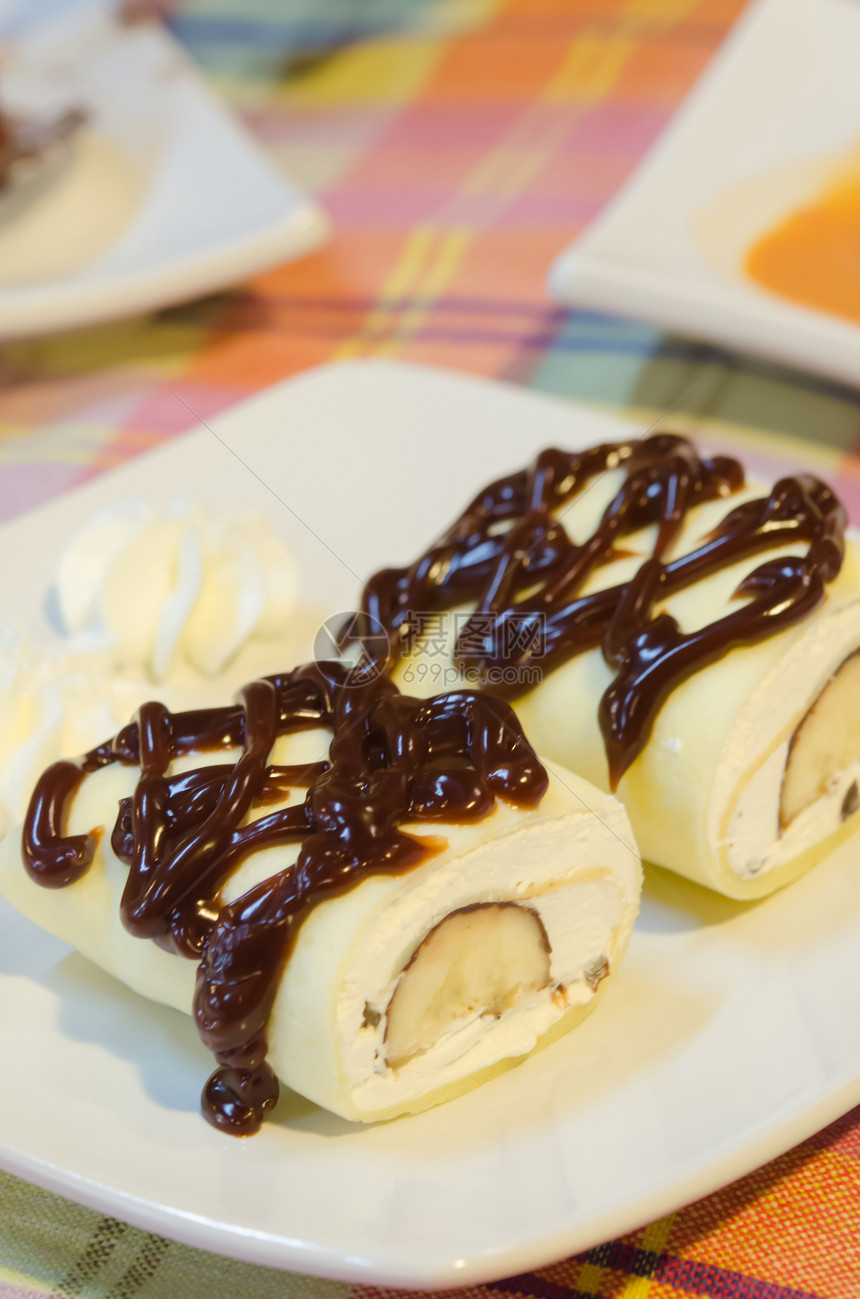 满白奶油和香蕉的冰淇淋胶卷加巧克力糖浆和盘子里的奶油图片