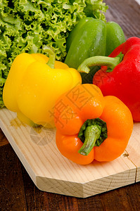 黄色红橙绿胡椒木盘上的生菜图片