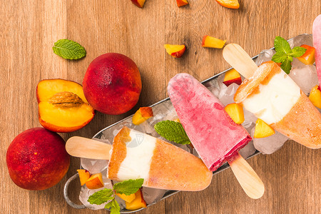 木桌上自制的草莓和桃子冰棒高清图片