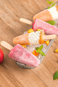 木桌上自制的草莓和桃子冰棒高清图片