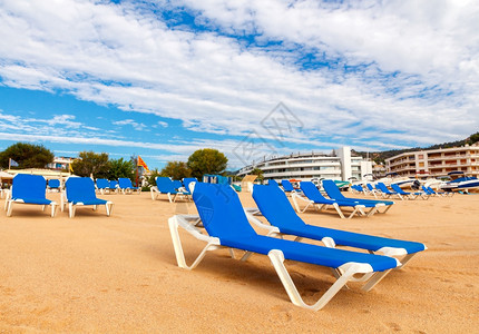 早上在TossadeMar海滩的蓝色休息椅图片