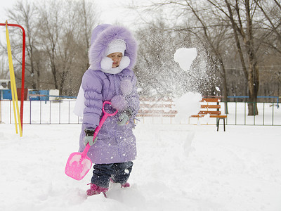 4岁的女孩用雪铲来铲雪背景图片